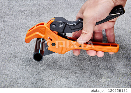PVC pipe tubing cutter, one hand ratchet pipe cutting tool for plastic pipes, on gray background. 120556182