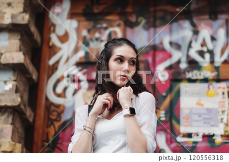 Young woman posing thoughtfully in front of colorful urban graffiti wall Young woman posing thoughtfully in front of colorful urban graffiti wall 120556318