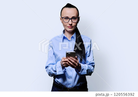 Middle aged serious woman with smartphone on white studio background Middle aged serious woman with smartphone on white studio background 120556392