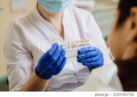 Dentist selecting a shade for dental veneers to ensure a perfect match for the patient's teeth 120556718