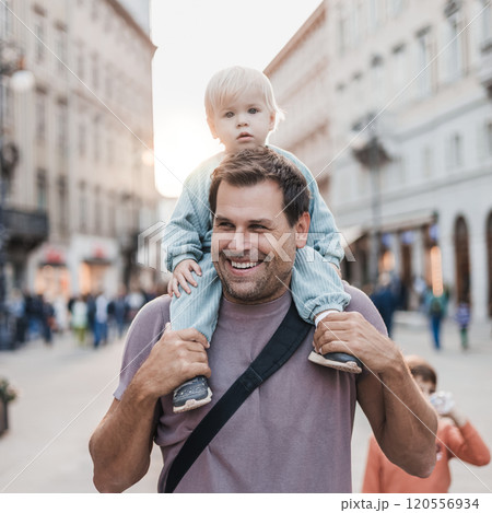Portrait of smiling father carrying his toddler child piggyback around city on family vacations. Happy father's day 120556934