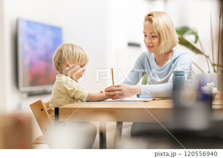 Caring young Caucasian mother and small son drawing painting in notebook at home together. Loving mom or nanny having fun learning and playing with her little 1,5 year old infant baby boy child Caring young Caucasian mother and small son drawing painting in notebook at home together. Loving mom or nanny having fun learning and playing with her little 1,5 year old infant baby boy child 120556940