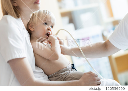 Small child being checked for heart murmur by heart ultrasound exam by cardiologist as part of regular medical checkout at pediatrician 120556990