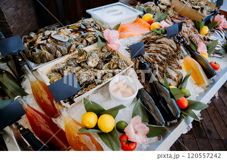 Seafood buffet display with oysters, shrimp, drinks, and fresh garnishes on ice for a gourmet feast 120557242