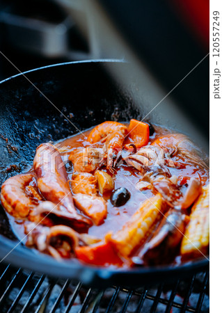 Seafood boil in a wok with shrimp, squid, corn, and rich sauce, cooking over a grill Seafood boil in a wok with shrimp, squid, corn, and rich sauce, cooking over a grill 120557249