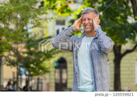 Displeased man rubbing temples to cure headache problem suffering from migraine stress on street Displeased man rubbing temples to cure headache problem suffering from migraine stress on street 120559921