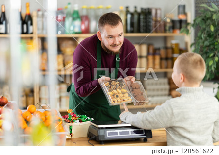 Male seller offers cookies to boy buyer 120561622