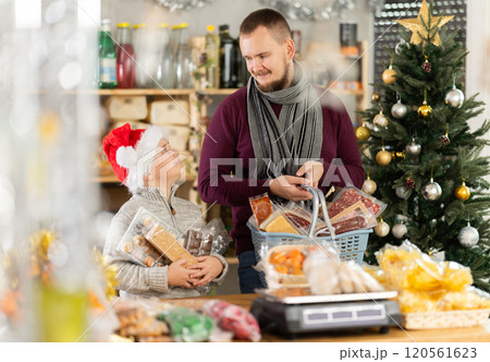Young man with son choosing sweets at grocery store 120561623