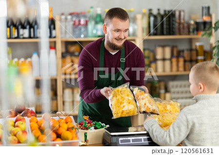 Male seller offers chips to boy buyer 120561631