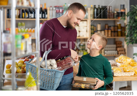 Young man with son choosing groceries in store 120562035
