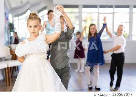 Little children in elegant dresses practicing waltz dance in school hall 120562077
