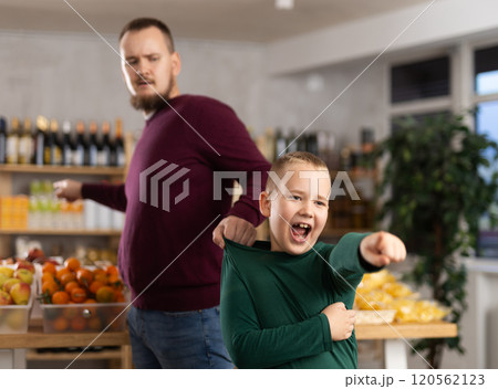 Angry dad dragging his little son behaving capricious in market Angry dad dragging his little son behaving capricious in market 120562123