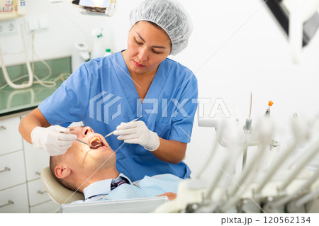 Focused woman dentist treats a man patient 120562134