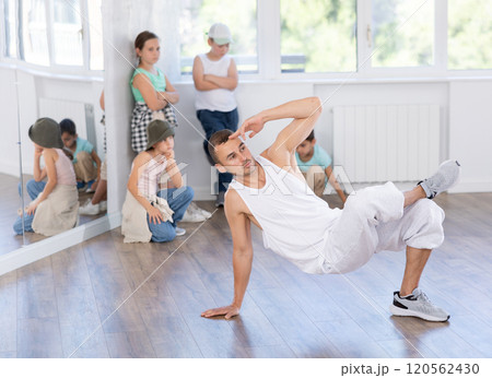 Dance teacher showing kids how to low break dance in studio 120562430