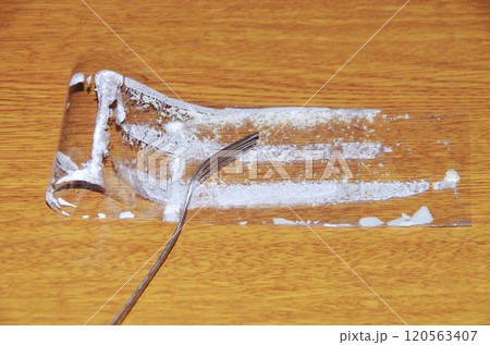 ショートケーキから剥がして折り曲げてフォークで押さえたフィルムの内側に白いクリームが付着している状態 120563407