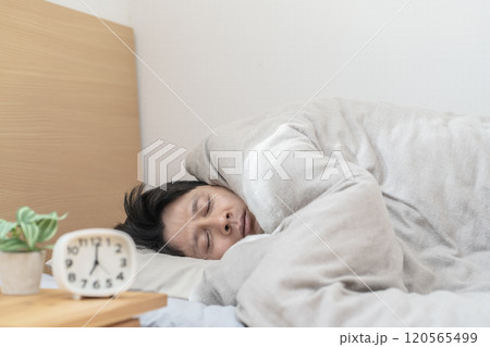 ベッドで眠る男性　寒くてベッドから出られない男性 120565499