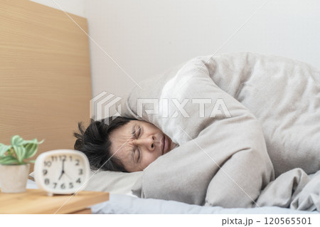 ベッドで眠る男性　寒くてベッドから出られない男性 120565501