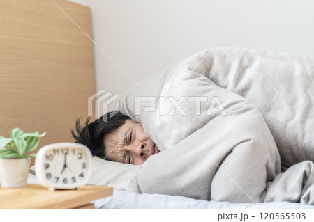 ベッドで眠る男性　寒くてベッドから出られない男性 120565503