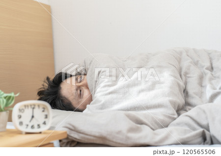ベッドで眠る男性　寒くてベッドから出られない男性 120565506