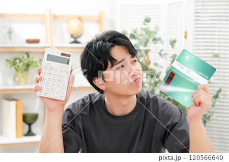 通帳を持って悩む男性 120566640