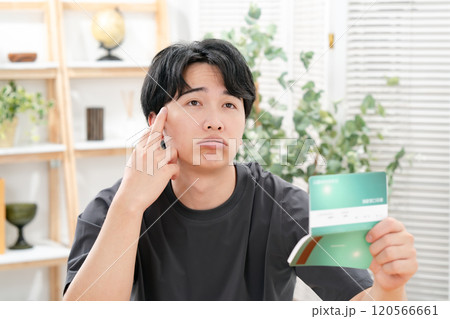 通帳を持って悩む男性 通帳を持って悩む男性 120566661