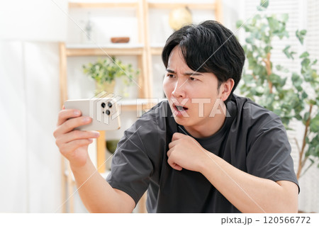 スマホを見て笑う男性 120566772