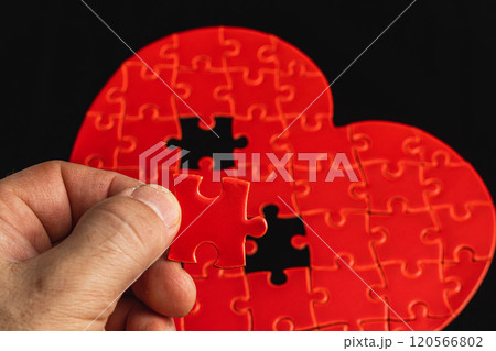 Concept of feelings in a puzzle. Hand puts missing pieces into a heart puzzle 120566802