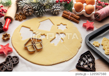 Baker is preparing christmas cookies using dough cutters and baking tray 120567380