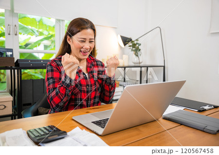 Asian Adult business woman indoors in home office working on laptop computer, happy female freelancer sitting at the home work on new project, businesswoman shopping online with computer 120567458