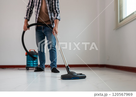Person Vacuuming Floor with Modern Vacuum Cleaner in Clean, Minimalistic Room 120567969