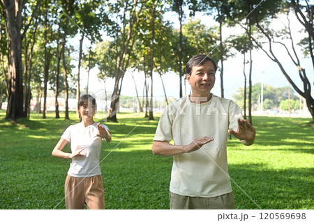 Calm father and daughter practicing Tai Chi in a serene park. Family activities, health and well being concept Calm father and daughter practicing Tai Chi in a serene park. Family activities, health and well being concept 120569698