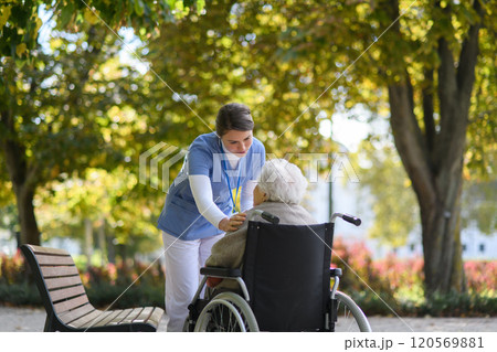 Disabled elderly woman in wheelchair talking with her nurse, sharing her problems with female caregiver. Disabled elderly woman in wheelchair talking with her nurse, sharing her problems with female caregiver. 120569881