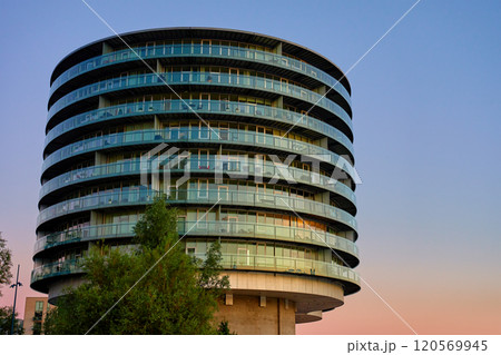 Modern round building with glass facade. Modern residential building with curved design at sunset. Detail of contemporary architecture 120569945