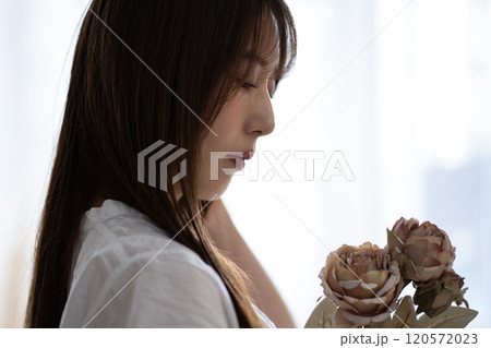 白い花を持つ黒髪ロングヘアの若い女性 120572023