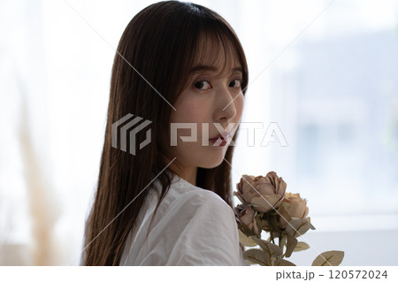 白い花を持つ黒髪ロングヘアの若い女性 120572024