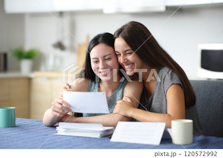 Happy interracial lesbian couple checking bill 120572992
