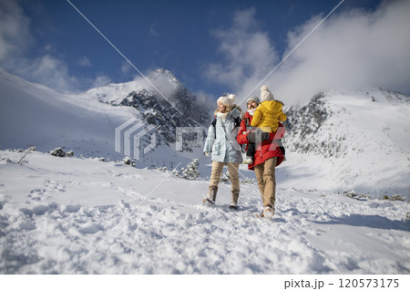 Young family is enjoying winter holiday in the mountains, playing and walking through the snowy landscape. 120573175