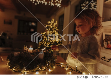 Little girl lighting candles on advent wreath. Little girl lighting candles on advent wreath. 120573256