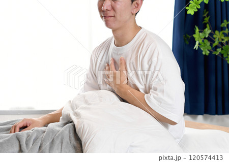 寝室で胸を抑えて苦しむ若いアジア人男性 120574413