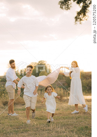 Happy young family dad, mom and two children playing outdoors, having fun on a day off. 120575200