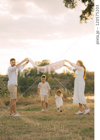 Happy young family dad, mom and two children playing outdoors, having fun on a day off. 120575203