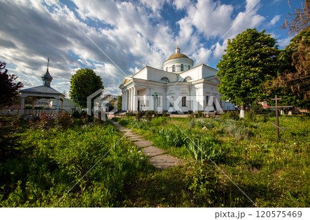 A scenic view of historic churche surrounded by greenery under a vibrant blue sky with scattered clouds. The architecture highlights cultural heritage and peaceful natural surroundings. 120575469
