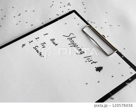 Holiday shopping list on festive clipboard with star confetti and seasonal decorations 120576038