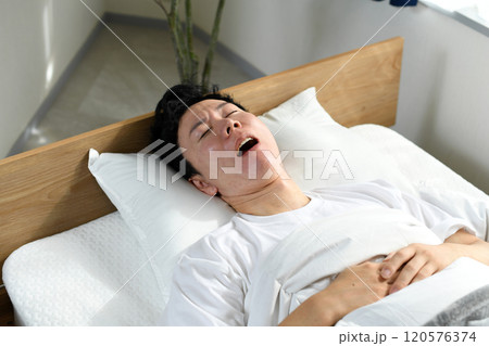 ベッドの上で口を開けて寝るアジア人男性 120576374