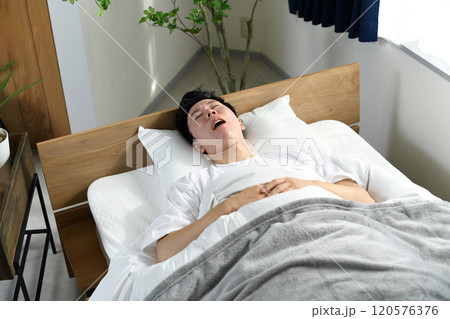 ベッドの上で口を開けて寝るアジア人男性 120576376
