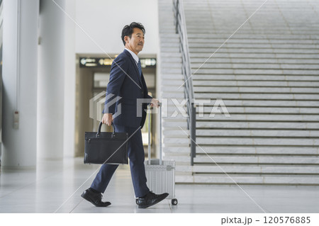キャリーバッグを持って歩く50代のビジネスマン　出張イメージ 120576885
