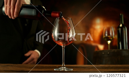 Close-up of red wine pouring into glass in wine cellar , freeze motion. 120577321