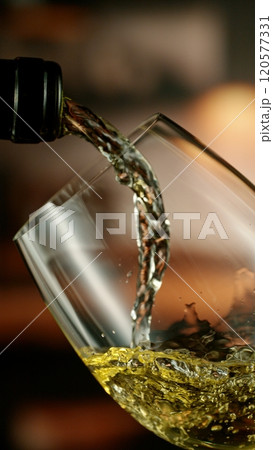 Close-up of white wine pouring into glass , freeze motion. Close-up of white wine pouring into glass , freeze motion. 120577331