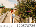 A woman carrying a backpack strolls leisurely along a picturesque pathway that is beautifully lined with lush greenery 120578726