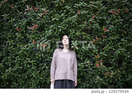 植込みの前に立つ女性 120579584